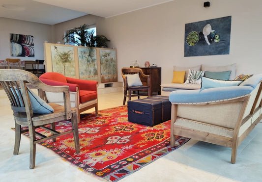 Kilim ancien Sarkisla 250x360 cm dans un salon au Luxembourg, fauteuil corail, canapé bleu, paravent peint, malle ancienne
