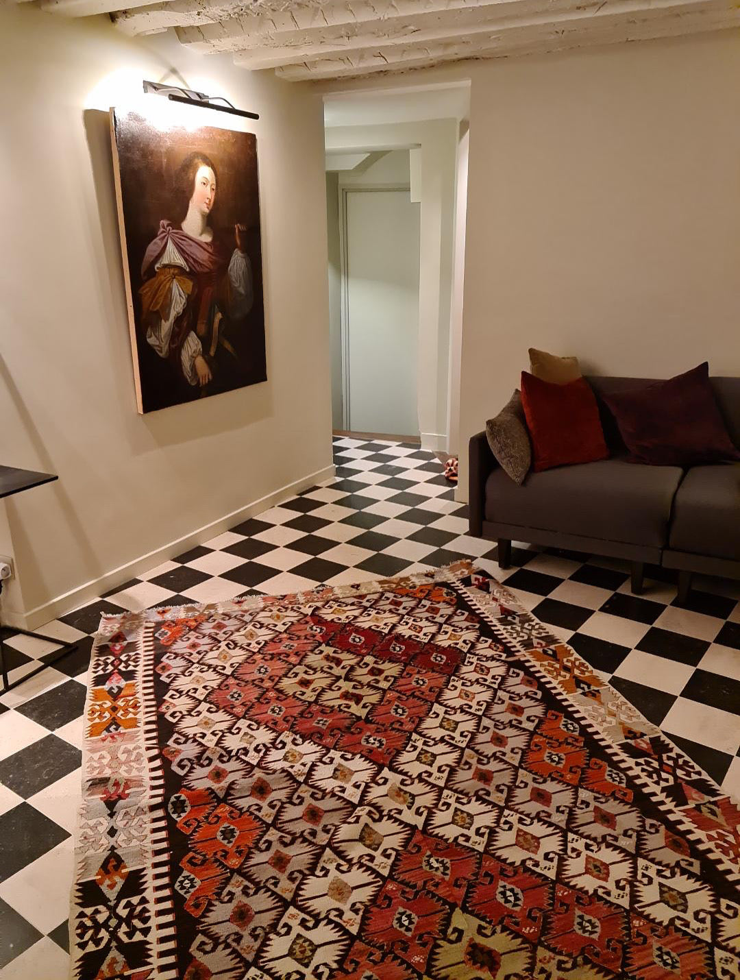 Kilim ancien Sivrihisar 280x172 cm posé dans un couloir parisien du 6ème arrondissement, sol en damier noir et blanc, portrait ancien au mur