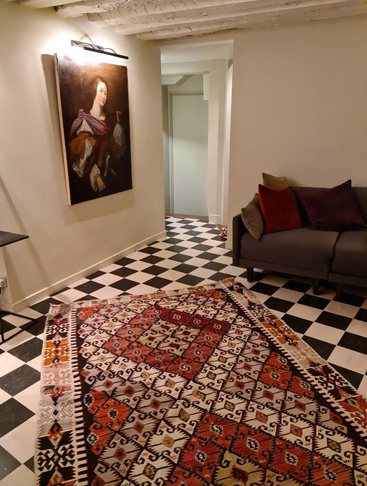 Kilim ancien Sivrihisar 280x172 cm posé dans un couloir parisien du 6ème arrondissement, sol en damier noir et blanc, portrait ancien au mur