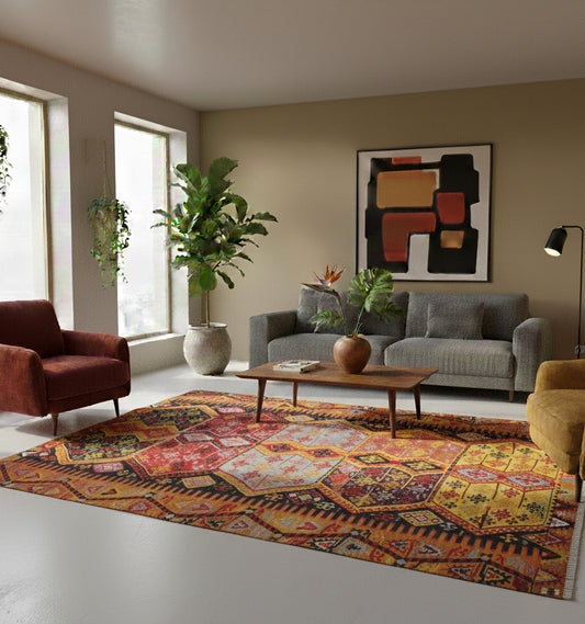 Grand tapis de salon en laine Malatya aux motifs géométriques jaune, ocre et rouge (280 x 180 cm) mis en situation dans un salon moderne avec canapé gris, fauteuils colorés, tableau abstrait et plantes suspendues