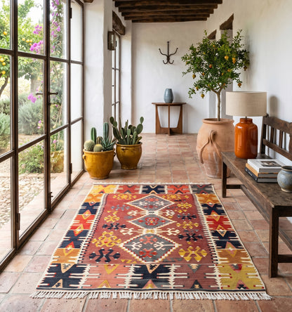 Kilim ancien de Pozantı, Anatolie, motifs géométriques rouge, ocre et indigo tissés main en laine naturelle, dans une entrée méditerranéenne lumineuse à Montpellier.