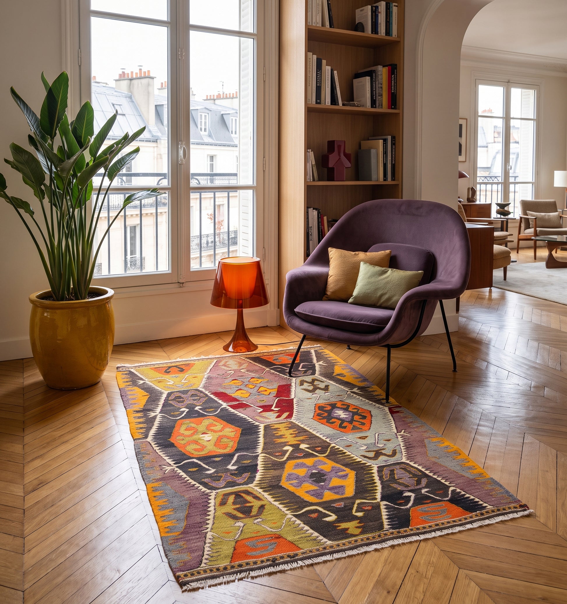 Kilim ancien Barak, tapis kilim tissé main en laine par des nomades d'Anatolie, mosaïque de losanges aux couleurs vives, posé dans un appartement parisien au parquet en chevrons face aux toits zinc