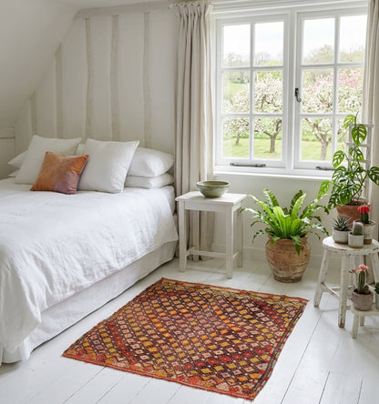 Kilim Cicim ancien en laine aux tons terre de Sienne et ocre, tissage artisanal d'Anatolie à motifs losanges, sublimant une chambre blanche lumineuse au style bohème chic et naturel.