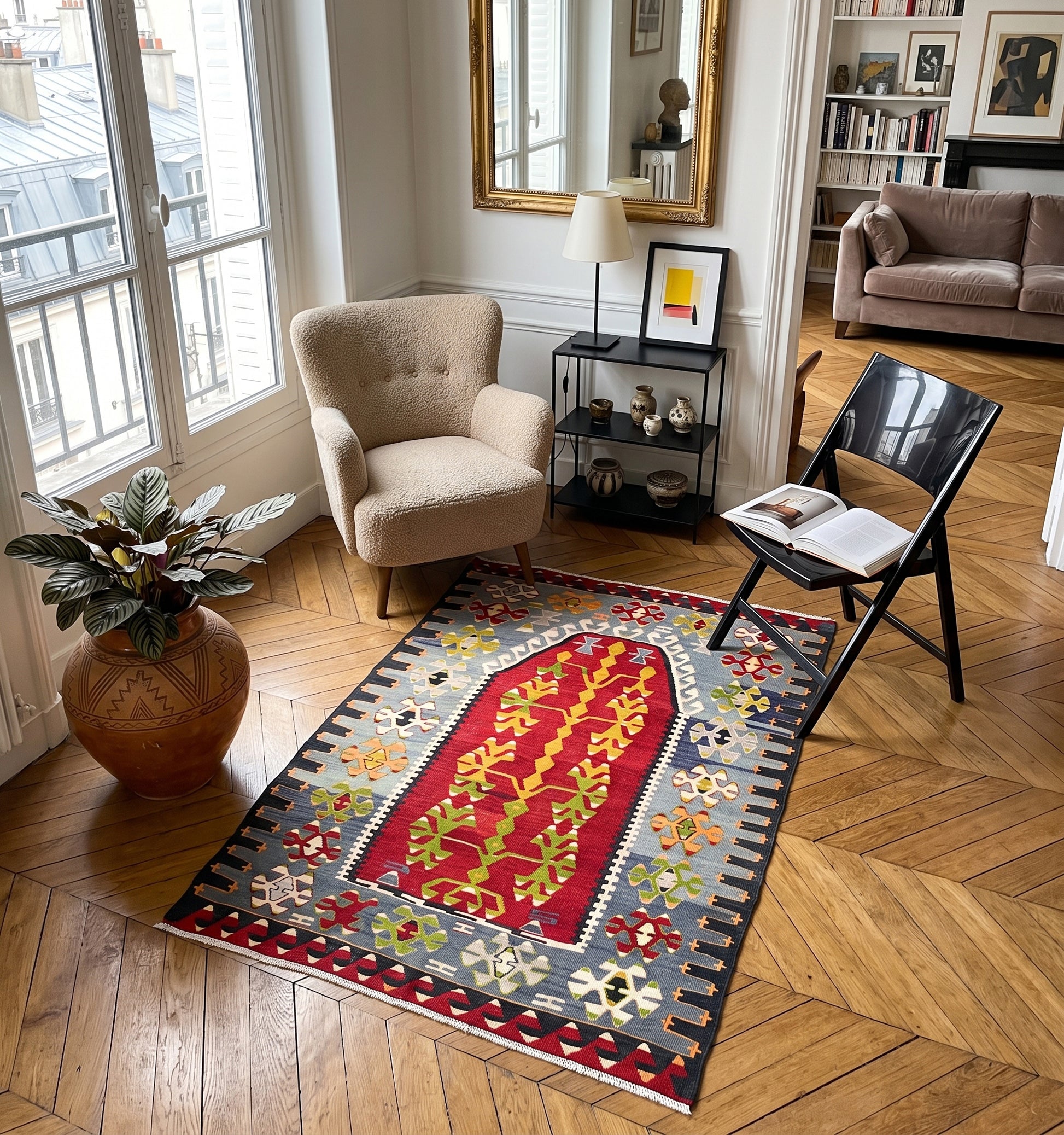 Kilim ancien d'Esme, tapis kilim tissé main en laine par des nomades d'Anatolie, médaillon rouge à motif d'arbre de vie, posé sur parquet en chevrons dans un appartement parisien face aux toits de zinc