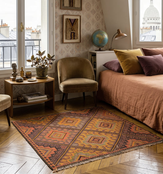 Fragment d'Anatolie vieux de 65 ans, kilim de Kağızman aux couleurs ocre et rouille patinées par le temps, posé sur parquet point de Hongrie dans une chambre bohème à Montmartre.