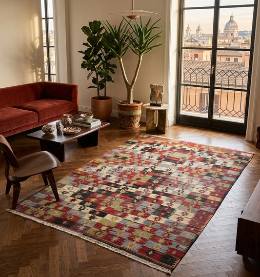 Kilim ancien Yesilova 300×180 cm dans un salon à Rome – canapé velours terracotta, parquet point de Hongrie, plantes tropicales et vue sur les toits de Rome.