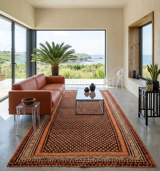 Kilim tapis salon d'Anatolie ancien tissé main aux motifs géométriques et teintes terracotta, créant un contraste intemporel et chic dans un salon moderne ouvert sur l'océan.