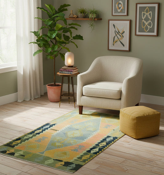 Tapis de salon en laine aux tons pastel jaune et bleu (148 x 90 cm) mis en situation avec un fauteuil crème, un pouf moutarde et des plantes vertes