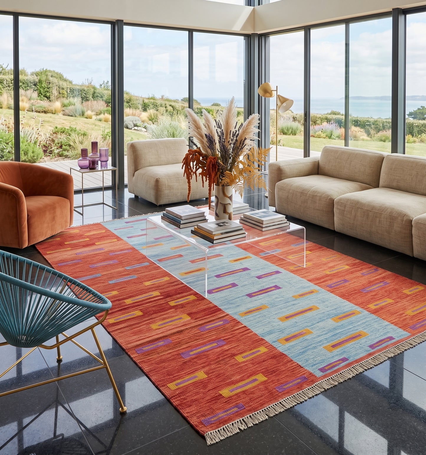 Kilim tissé main aux motifs géométriques rythmés sur fond bicolore corail et bleu, tapis kilim contemporain d'inspiration Anatolie posé dans une villa en Bretagne face à l'océan, pièce unique aux lignes vives