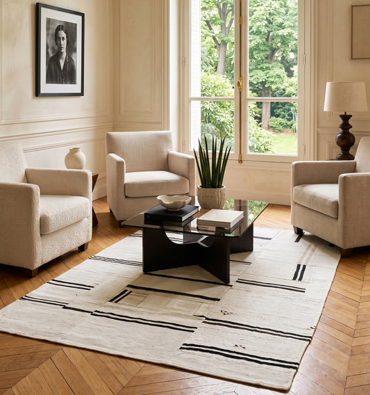 Kilim patchwork en chanvre, tapis contemporain tissé main à partir de kilims anciens d'Anatolie recomposés, motif rayé noir et écru posé sur parquet en chevrons dans un salon parisien haussmannien