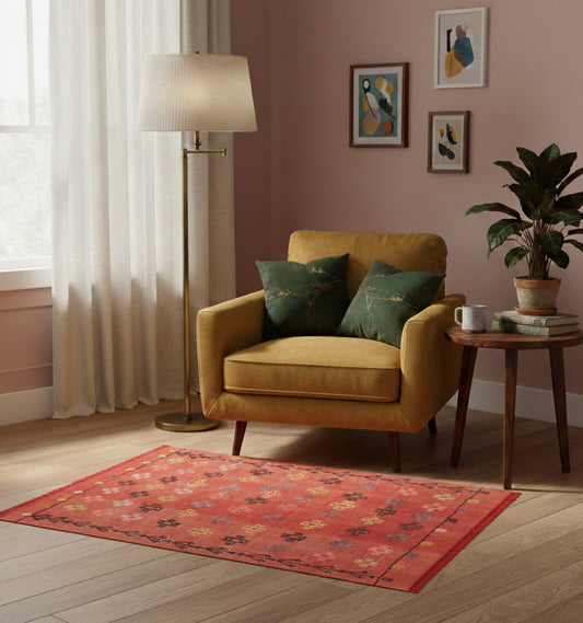 Petit tapis en laine Adana orange aux motifs floraux délicats (125 x 98 cm) idéal pour une chambre ou un coin lecture, présenté avec un fauteuil jaune moutarde et des murs vieux rose