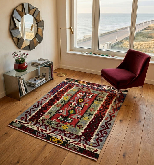 Kilim anatolie au Touquet aux motifs tribaux complexes et colorés, apportant une âme artisanale à un salon contemporain avec vue sur mer, canapé en velours bordeaux et mobilier design.