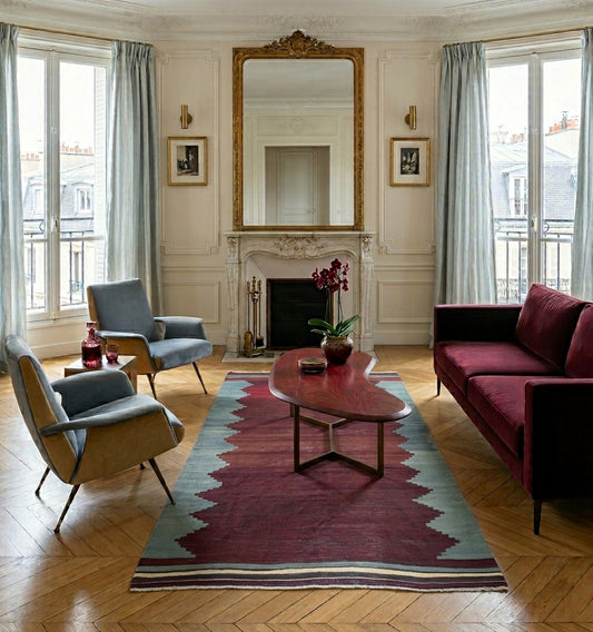 Tapis Kilim Balikesir vintage rouge et gris en laine dans un salon haussemanien à Paris avec du parquet au sol, canapé prunet et fauteuil design bleu