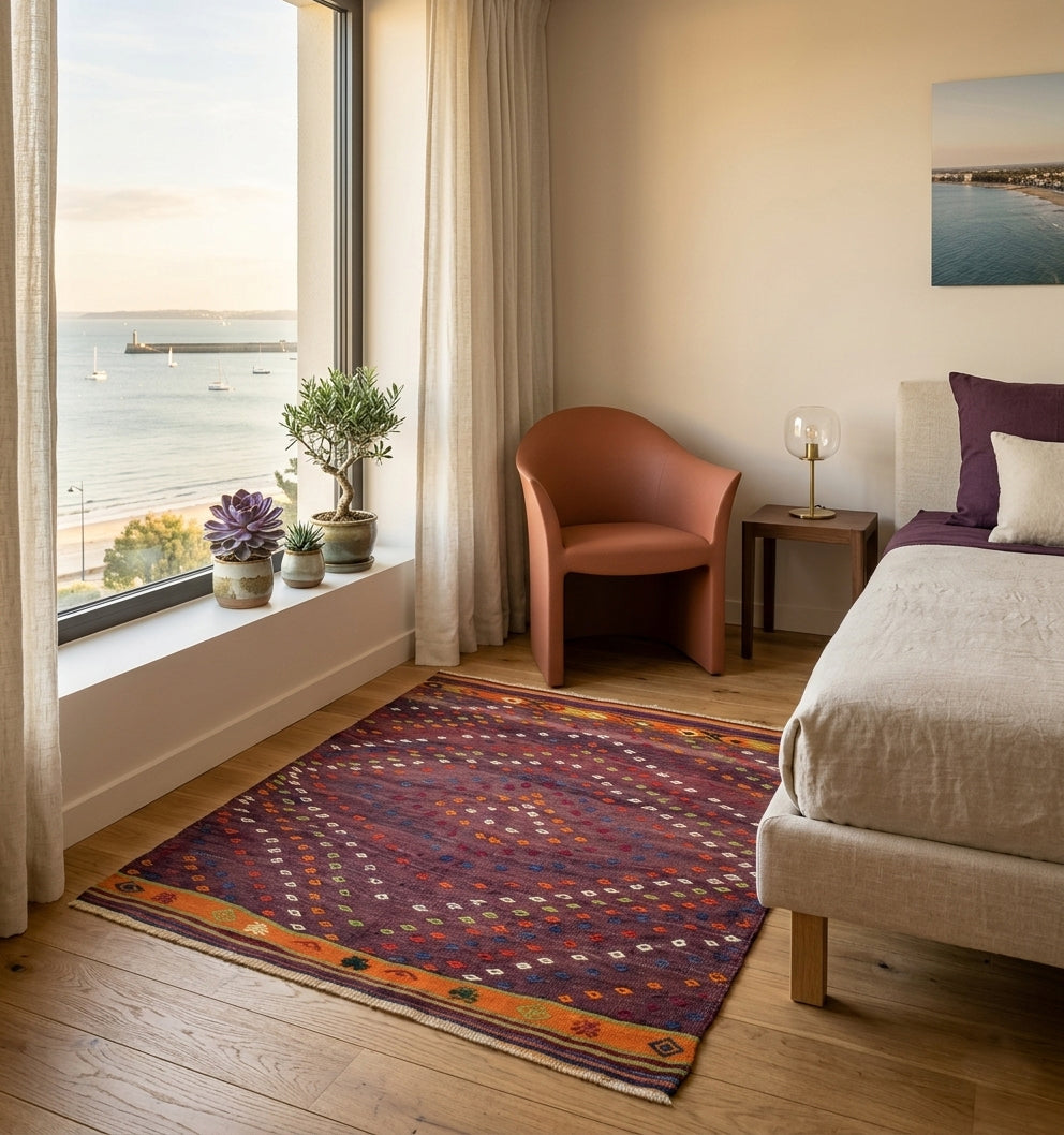 Tapis kilim ancien Anatolie violet au tissage artisanal géométrique dans une chambre moderne chic avec vue mer.