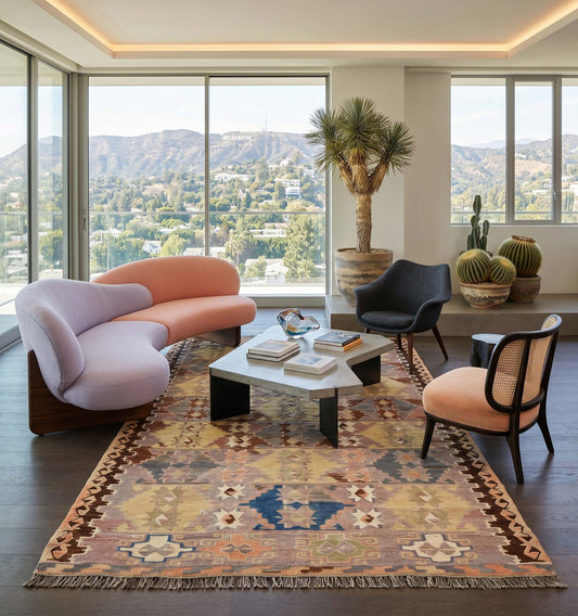 Grand tapis kilim Antalya de 70 ans aux tons pastel et motifs ancestraux, tissé à la main en Anatolie. Cette pièce de collection magistrale sublime le salon d'une villa de luxe à Los Angeles, créant un contraste saisissant entre l'artisanat turc vintage, un mobilier design organique et une vue panoramique prestigieuse.