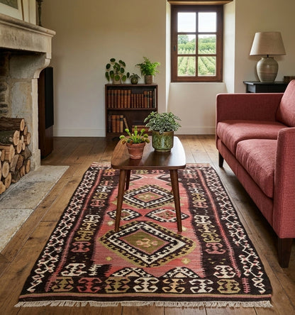 Petit tapis kilim Bakirdag ancien (160 × 97 cm) aux motifs géométriques chocolat et rose poudré, mis en situation dans un salon de campagne chic avec parquet en chêne, canapé terracotta, table basse en bois sombre et vue sur un vignoble par la fenêtre.