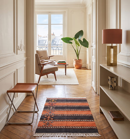 Tapis kilim cicim ancien, tissé main en laine par des nomades d'Anatolie, technique brodée à rayures orange et noir, posé dans un couloir d'appartement à Versailles orné de boiseries et moulures