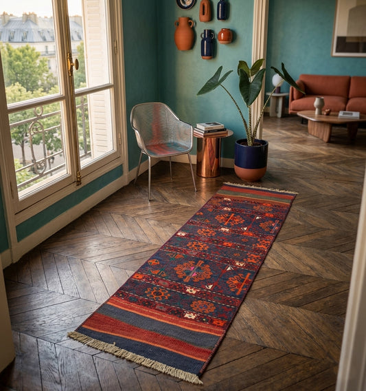 Galerie de tapis kilim d'Anatolie aux motifs floraux stylisés bleu et orange, sur un parquet en point de Hongrie dans un appartement parisien au design contemporain et murs vert canard.