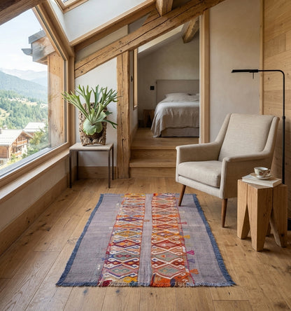Tapis kilim Cuval vintage de 60 ans, tissé à la main en Anatolie avec des pigments naturels. Ce petit format aux motifs losanges est mis en valeur dans un chalet de luxe à Megève, apportant une chaleur artisanale et un caractère authentique à une chambre moderne en bois clair.