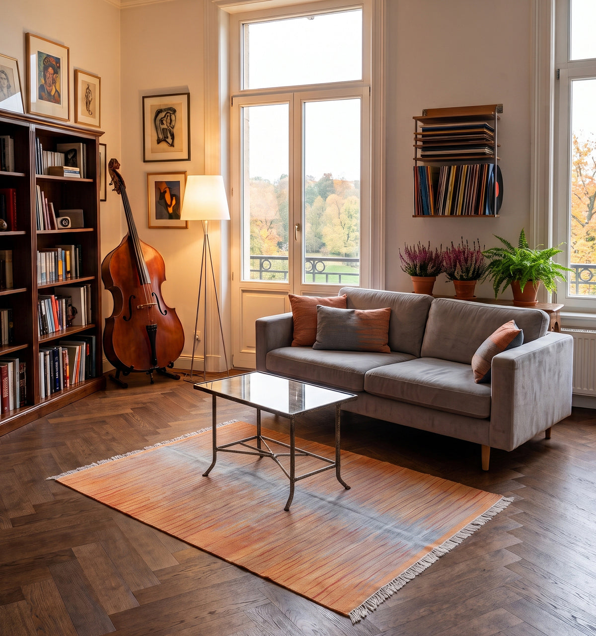 Tapis kilim tissé main aux rayures dégradées corail et gris, tapis contemporain d’inspiration Anatolie posé sur parquet en chevrons dans un salon à Reims face à une bibliothèque et une vue sur le parc en automne