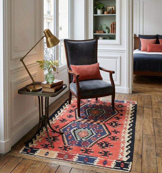 Tapis kilim ancien d'Anatolie aux motifs géométriques rouge et bleu. Véritable tissage artisanal turc disposé dans un intérieur chic à la française, sublimant le contraste entre l'artisanat ancestral et la décoration moderne.