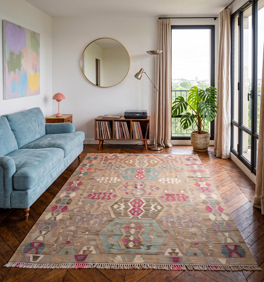 Tapis kilim tissé main aux médaillons hexagonaux rose poudré et vert d'eau, tapis contemporain d'inspiration Anatolie posé dans un appartement à Boulogne-Billancourt face à la vue sur les arbres, pièce unique aux teintes douces