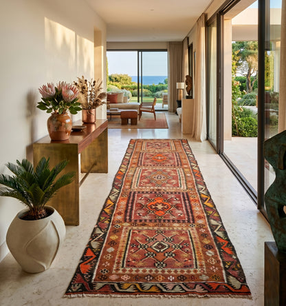 Tapis kilim Kayseri ancien au format galerie (398 x 117 cm), tissé à la main en Anatolie avec des motifs géométriques et des teintes chaudes. Cette pièce de collection artisanale sublime une entrée de villa lumineuse à Saint-Tropez, créant une transition élégante sur un sol en terre cuite vers une vue panoramique sur la mer Méditerranée et les bateaux, dans une ambiance Riviera chic.