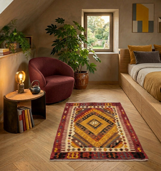 Tapis kilim d'Anatolie ancien aux motifs de losanges ocre et rouge, tissage artisanal traditionnel sur un parquet en chevrons dans une chambre design contemporaine.