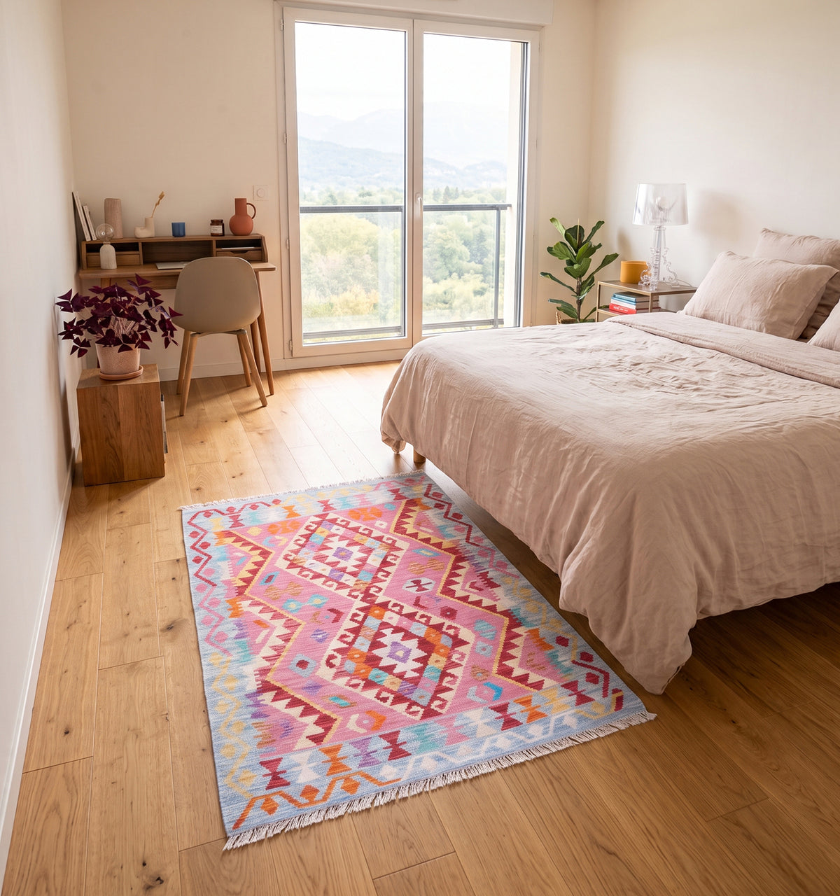 Tapis kilim tissé main au médaillon losangé rose fuchsia et corail, tapis contemporain d’inspiration Anatolie posé dans une chambre à Chambéry face à un bureau en bois et la vue sur les montagnes