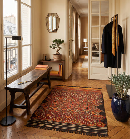Tapis kilim ancien Menemenci, tissé main en laine par des nomades d'Anatolie, réseau de losanges rouge et safran, posé dans un vestibule proche de la rue Saint-Honoré face aux fenêtres à persiennes