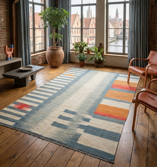 Tapis kilim contemporain d'Anatolie aux motifs graphiques bleu et ocre à Bruges, tissé main, sublimant un loft chic au parquet en chêne. Le design épuré de ce kilim ancien revisité se marie parfaitement avec un mobilier minimaliste et une architecture industrielle. Une pièce d'artisanat d'exception par Anatolie Kilim.