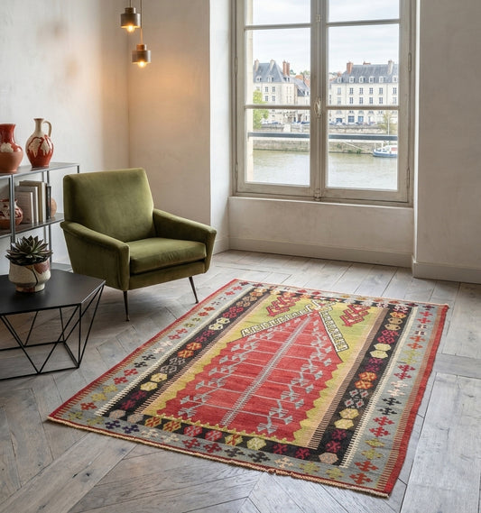 Grand tapis kilim Obruk ancien de 65 ans, tissage artisanal d'Anatolie aux motifs complexes. Cette pièce de collection aux tons rouges et verts sublime un salon élégant à Lyon, offrant un contraste saisissant entre l'héritage turc et un mobilier contemporain chic face aux quais.
