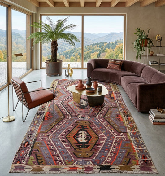 Grand tapis de salon en laine aux motifs géométriques (260 x 145 cm) mis en situation dans un intérieur moderne avec canapé violet et fauteuil en cuir design.