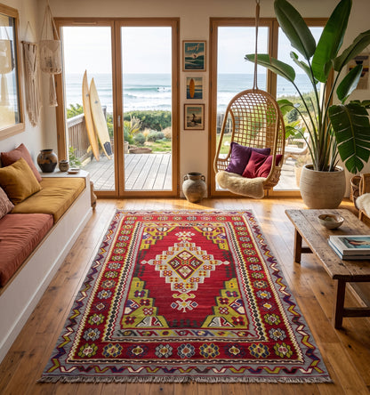 Tapis de salon en laine Usak rouge avec médaillon central crème et bordures géométriques (265 x 160 cm) mis en situation dans un salon rustique avec canapé violet, cheminée en pierre et sol en terre cuite