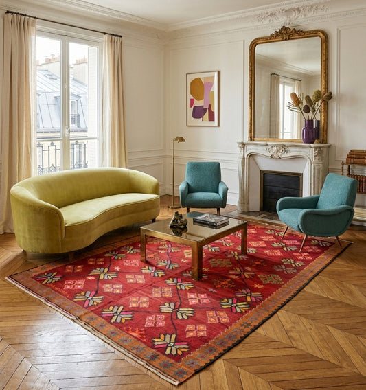 Grand tapis de salon en laine rouge aux motifs étoilés vintage (310 x 190 cm) mis en situation dans un intérieur moderne à Paris avec canapé pistache, fauteuils bleu, table basse design et décoration murale abstraite.
