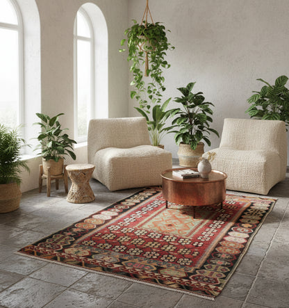 Tapis de salon ou d'entrée en laine rouge et ocre (172 x 125 cm), mis en situation dans un intérieur lumineux avec fauteuils blancs et table basse en cuivre.