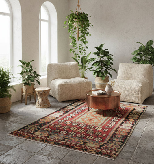 Tapis de salon ou d'entrée en laine rouge et ocre (172 x 125 cm), mis en situation dans un intérieur lumineux avec fauteuils blancs et table basse en cuivre.