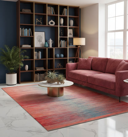 Grand tapis de salon en laine Art Deco avec dégradé horizontal rouge corail et bleu pétrole (298 x 197 cm) mis en situation avec un canapé vieux rose, une table basse en marbre et une grande bibliothèque sombre