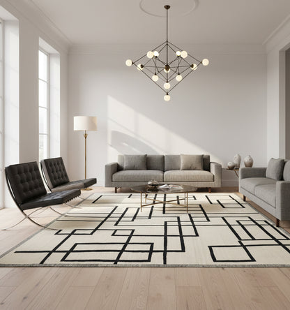 Très grand tapis de salon en laine Art Deco blanc à motifs géométriques noirs (303 x 193 cm) mis en situation dans un salon spacieux avec canapés gris, fauteuils Barcelona et lustre monumental