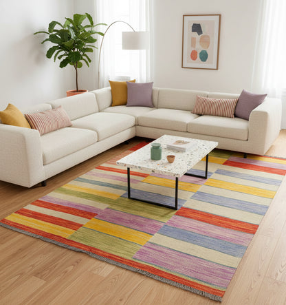 Grand tapis de salon en laine Art Deco aux larges rayures multicolores (203 x 154 cm) mis en situation avec un canapé d'angle blanc et une table basse en terrazzo