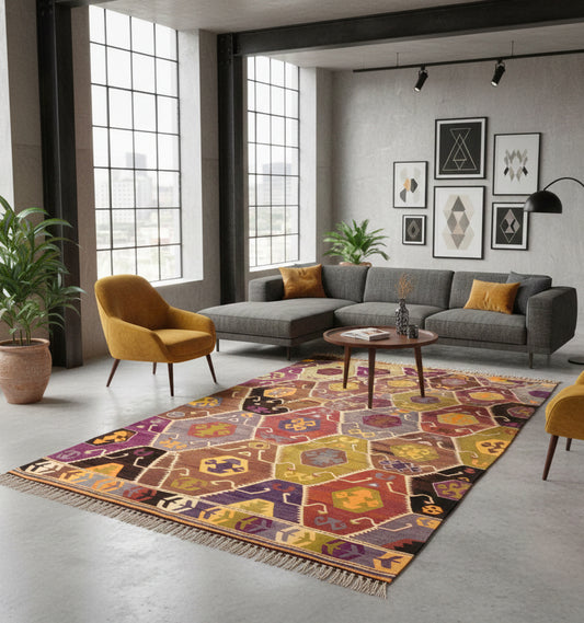 Grand tapis de salon en laine Barak aux motifs d'hexagones géométriques ocre, violet et vert (290 x 155 cm) mis en situation dans un salon de style industriel avec canapé gris anthracite, fauteuils jaune moutarde et murs en béton brut