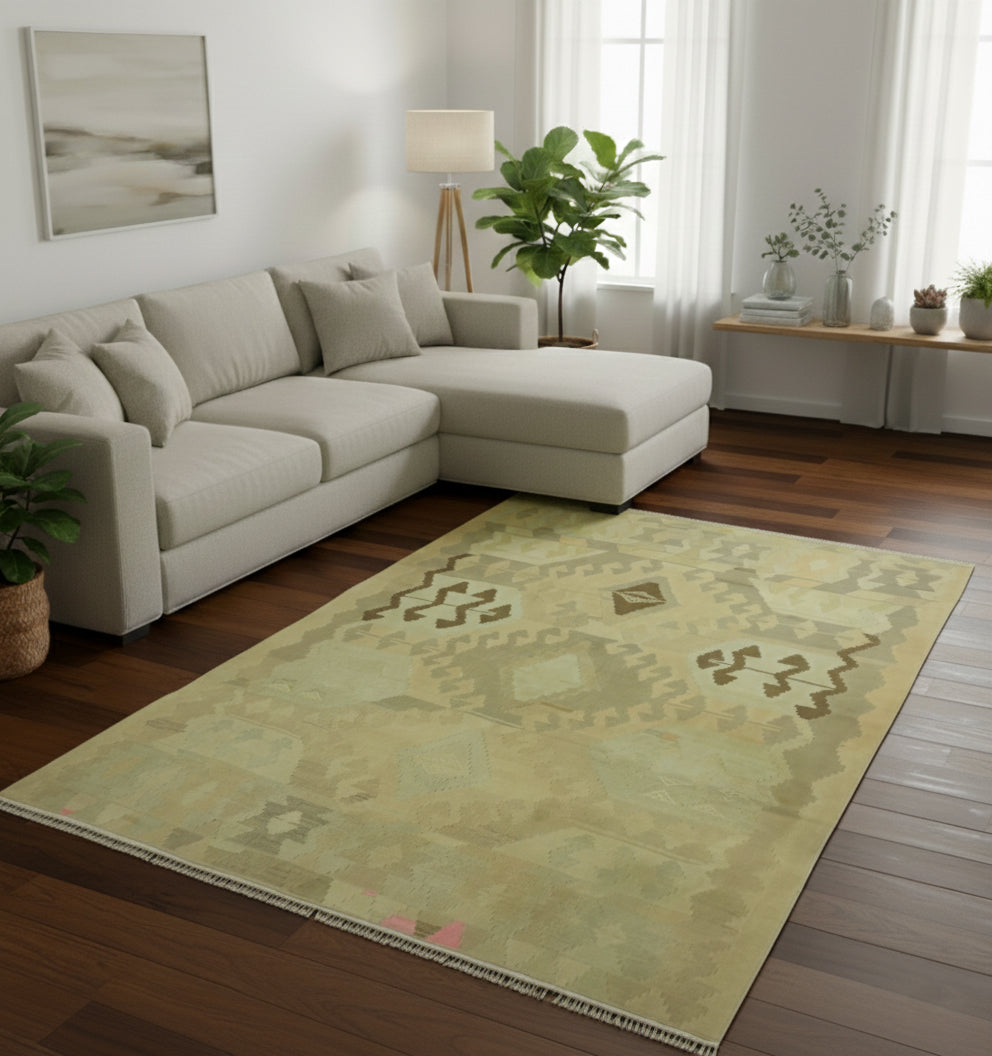 Tapis de salon en laine Kazak vert olive avec motifs tribaux géométriques délavés (290 x 190 cm) mis en situation avec un canapé d'angle crème et un parquet en bois foncé