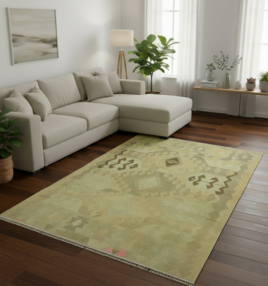 Tapis de salon en laine Kazak vert olive avec motifs tribaux géométriques délavés (290 x 190 cm) mis en situation avec un canapé d'angle crème et un parquet en bois foncé