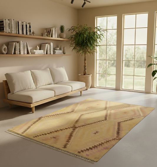 Tapis de salon kilim Barak en laine jaune aux motifs de losanges (260 x 150 cm) mis en situation dans un intérieur minimaliste avec canapé en bois clair, étagères murales fournies et grandes fenêtres lumineuses
